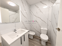 Baño moderno con mármol y logo inmobiliario.png