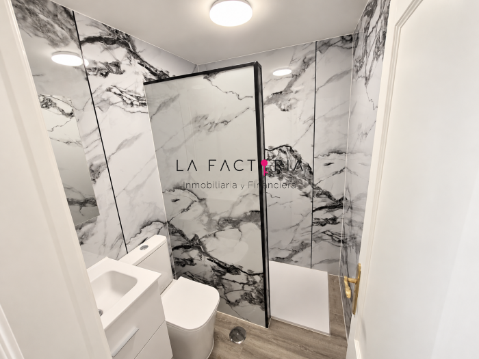 Baño moderno con mármol y ducha de cristal.png